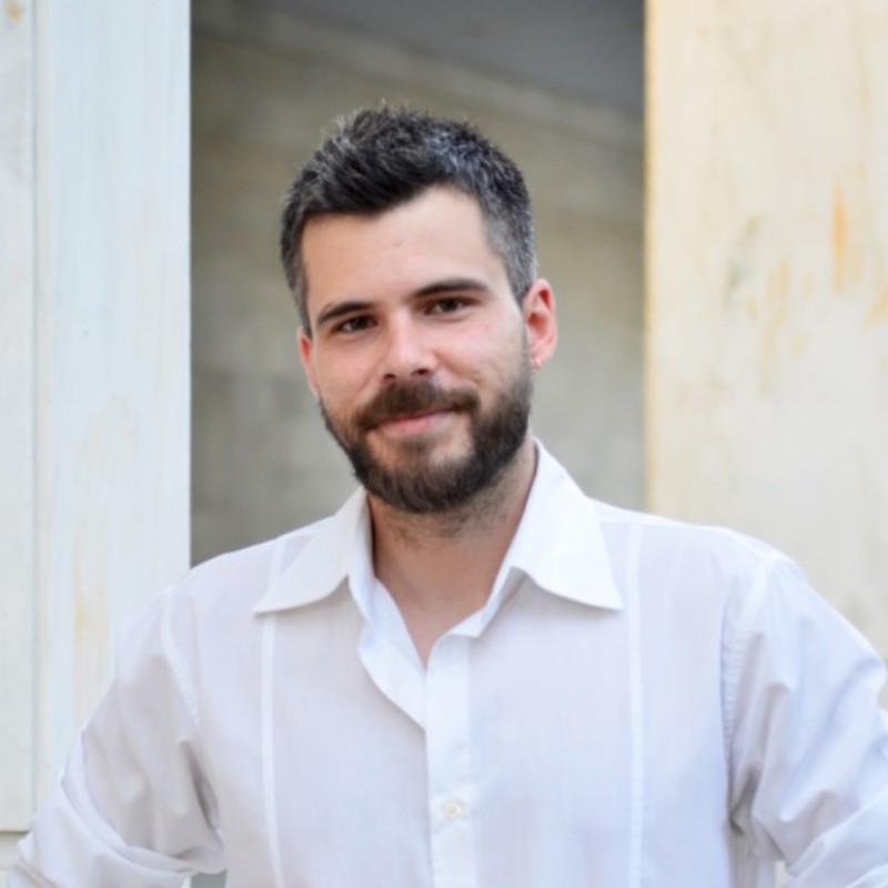 George Metaxiotis - Fresh Thinking Labs Smiling man with dark hair and beard wearing a white button-down shirt, standing in a doorway.