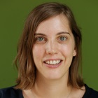 Karolien-Lenaerts - Fresh Thinking Labs Portrait of a smiling woman with shoulder-length brown hair against a green background, looking at the camera.