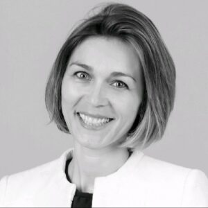 Head-and-shoulders portrait of a smiling woman with a short bob haircut in a light blazer.
