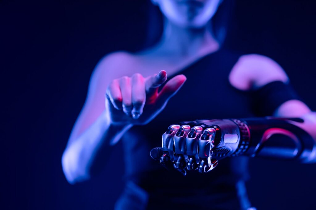 Close-up of a metal prosthetic hand with exposed gears reaching toward a surface in blue light.